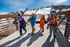 Kids walking with skis down bridge