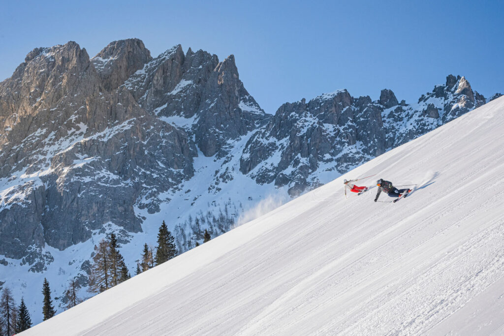 Two people skiing down run at 3 Zinnen Dolomites in Italy on a Sunny Day