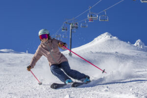 Woman skiing down slopes on a sunny day at Mt. Bachelor Ski Resort