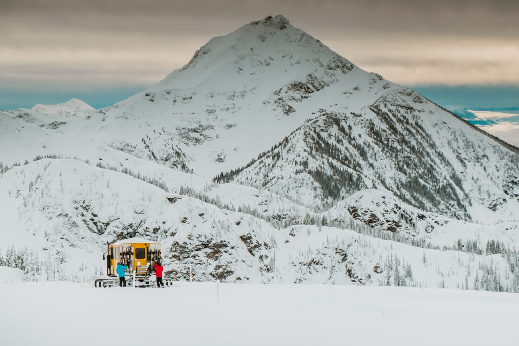 Cat skiing beneath snowy mountain peak