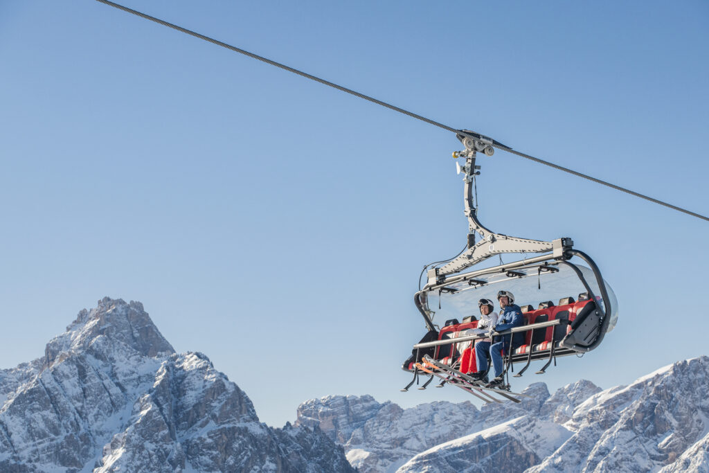 Couple on chairlift at 3 Zinnen Dolomites with mountain behind them
