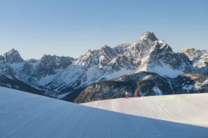 Skiers taking a break on groomed run at 3 Zinnen Dolomites