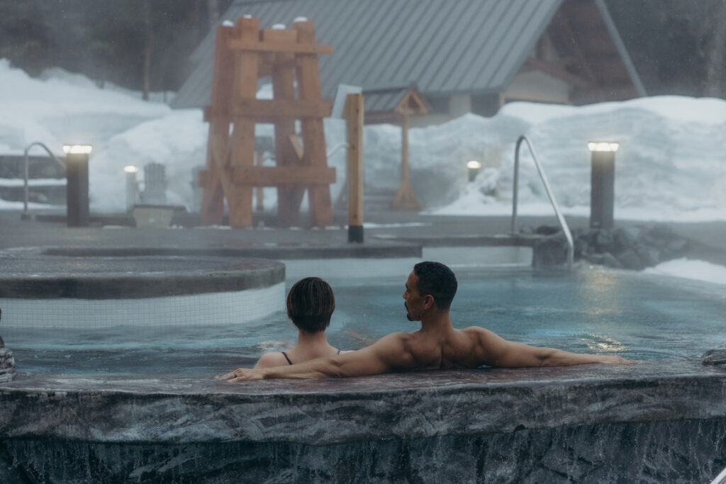 Couple enjoying a soak in pool at Alyeska Nordic Spa during the winter