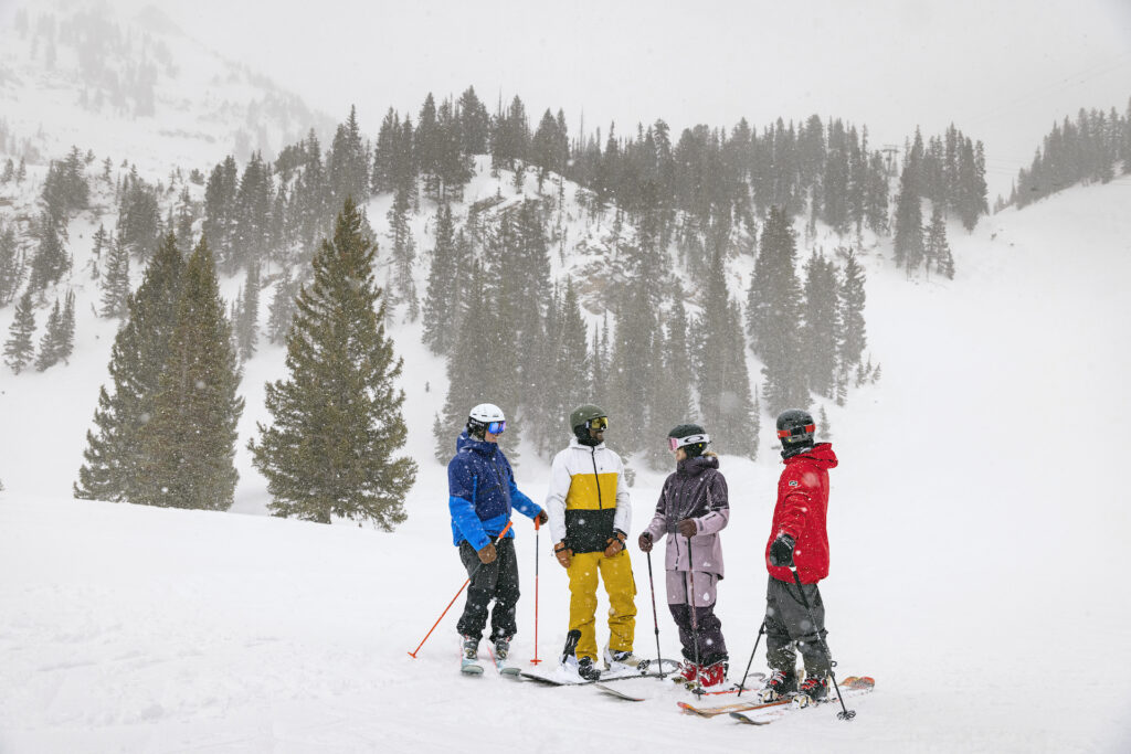 Group of friends taking a break on ski slopes while snow falls