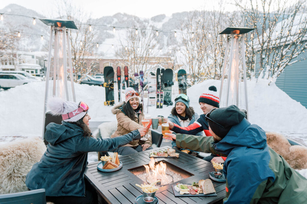Friends toasting glasses on Aspen patio on a winter day
