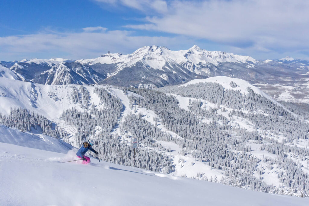 Skiing through powder on a sunny powder day in Telluride