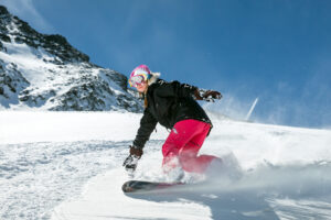 Woman snowboarding down slopes on a sunny day