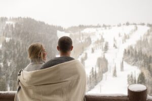 Couple standing on balcony overlooking ski slopes