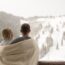 Couple standing on balcony overlooking ski slopes