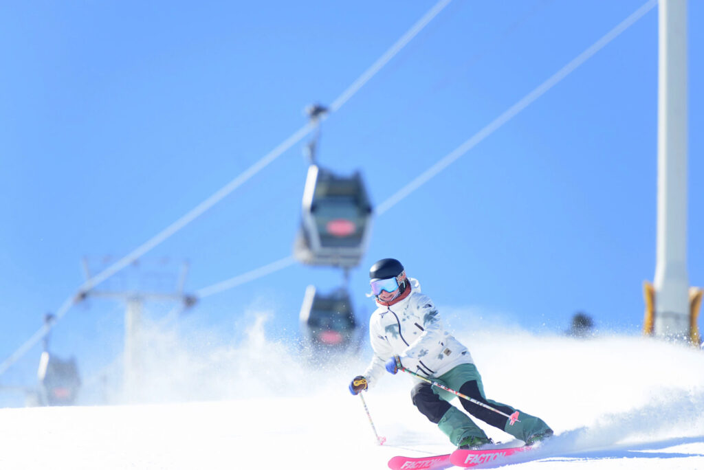 Skiing on groomed run underneath gondola at Stratton Mountain on a sunny day