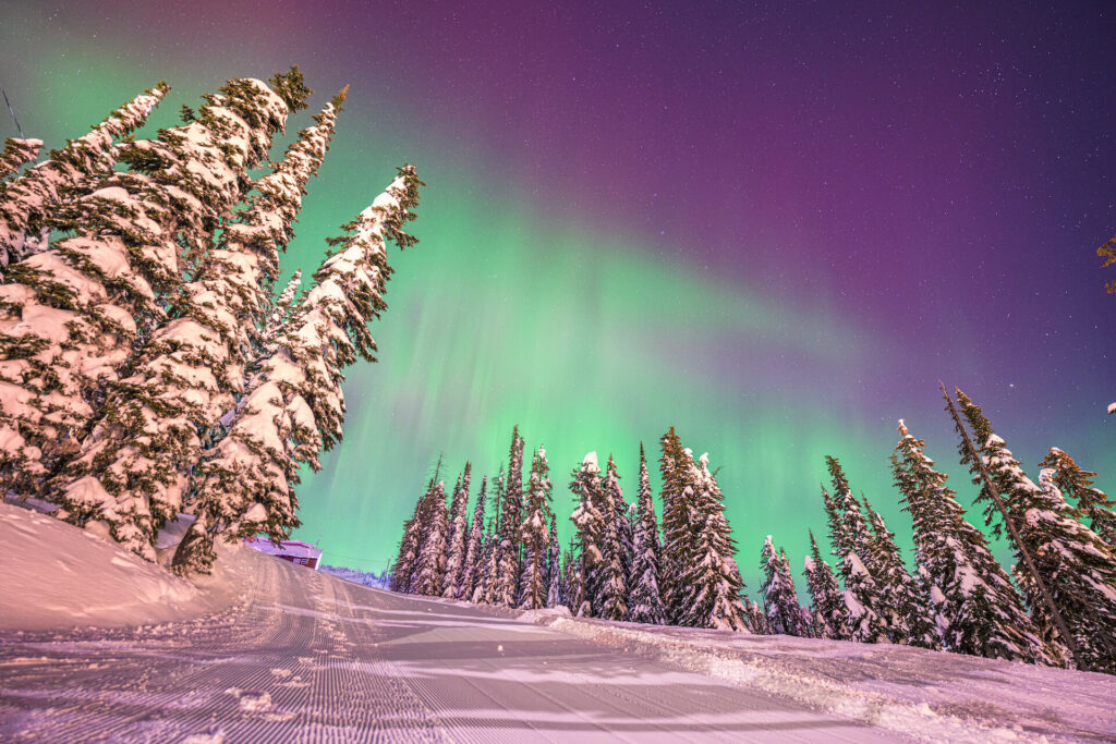 Northern Lights above a groomed ski run at Big White Ski Resort in Canada