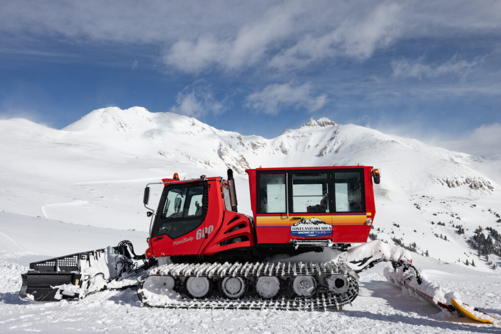 Loveland Ski Area snowcat parked with snow-covered mountains behind it