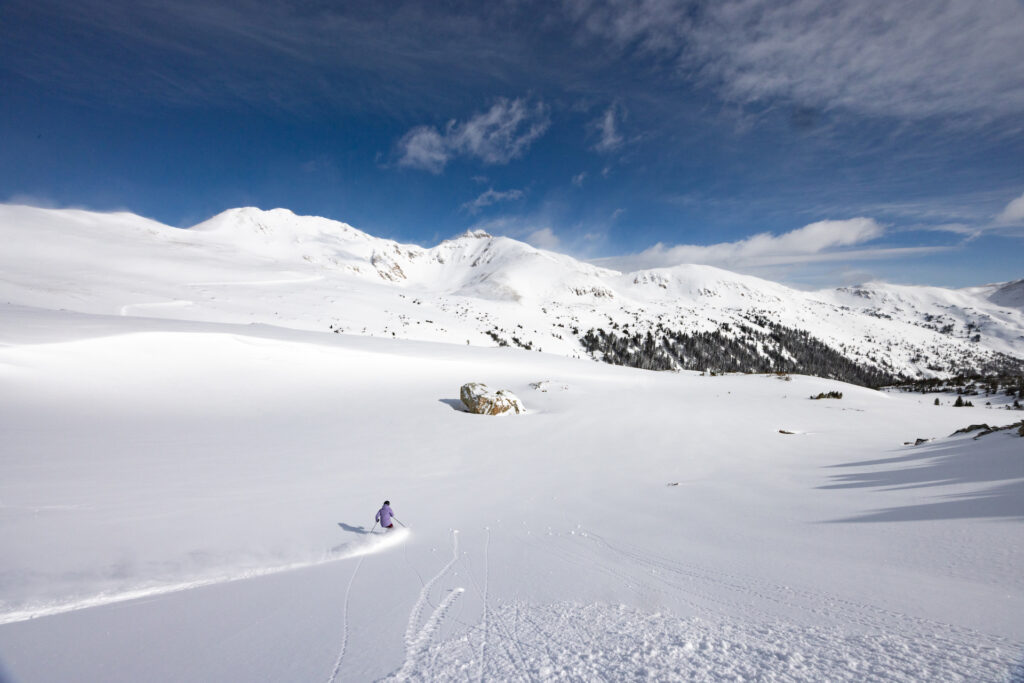 Person skiing through untracked powder on a sunny day at Loveland Ski Area