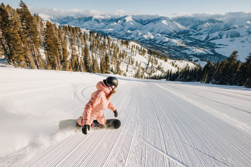 Snowboarding down a groomed ski run at Sun Valley Ski Resort on a bluebird day
