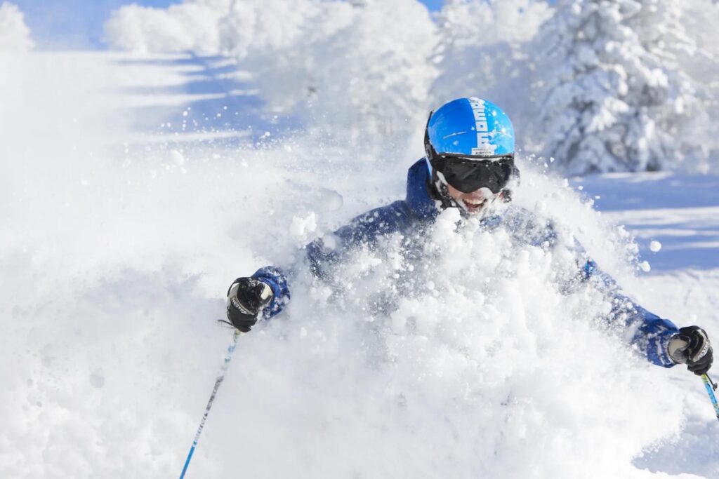 Skier grinning as they ski through deep powder in Japan