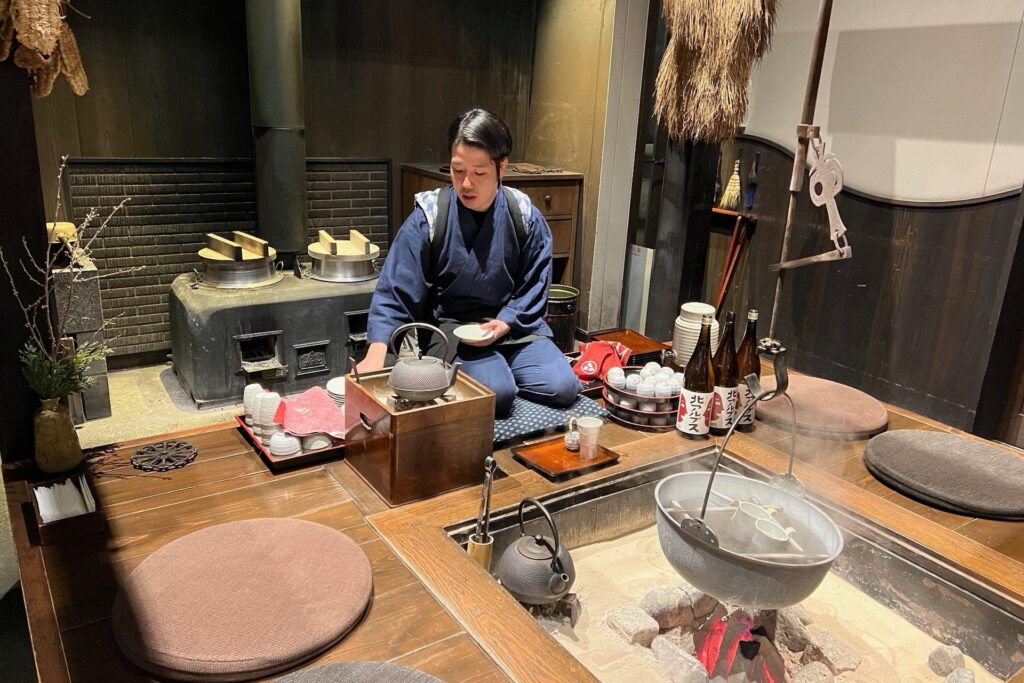 Person enjoying hot Japanese sake warming by fire at Hoshino Resorts KAI Alps
