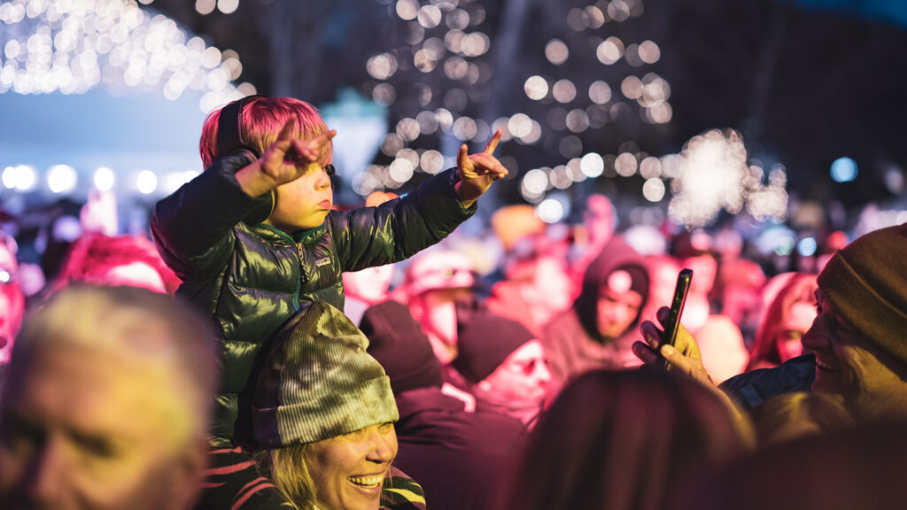 Kid on shoulders of parents enjoying music at Rendezvous festival at Jackson Hole