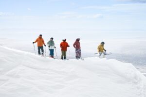 Group of friends skiing and snowboarding steep drop
