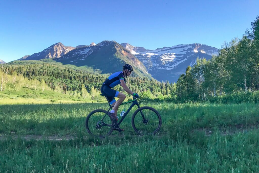 Biking down trail with mountains in the background